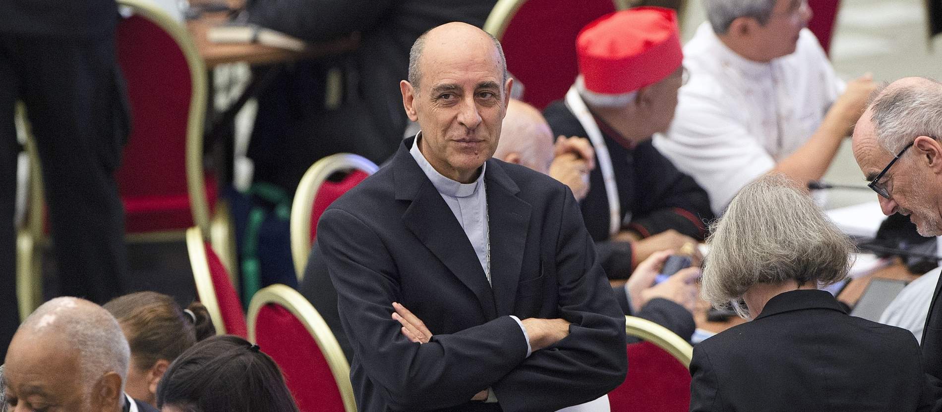 Kardinal Víctor Manuel Fernández steht mit verschränkten Armen in der Synodalaula