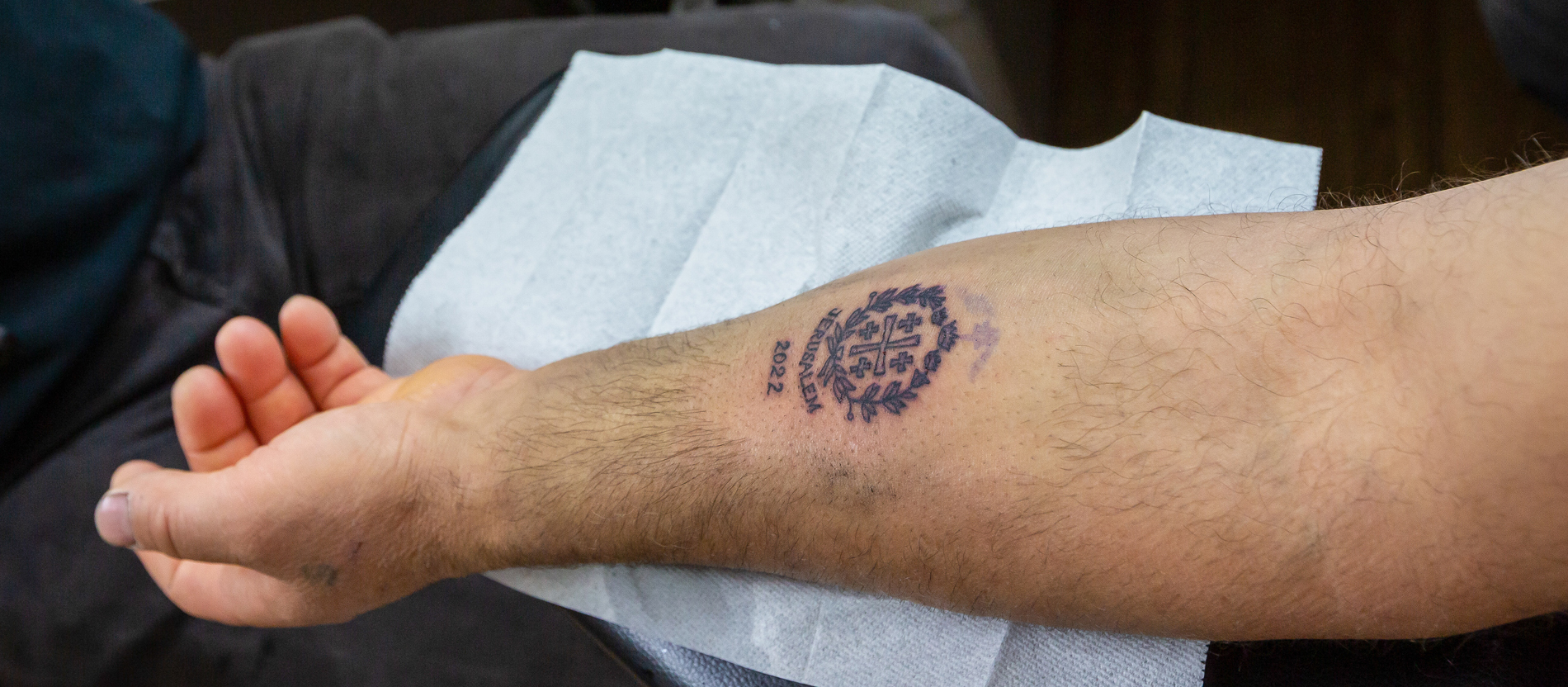 Jerusalemkreuz als Tattoo auf dem Arm eines Pilgers