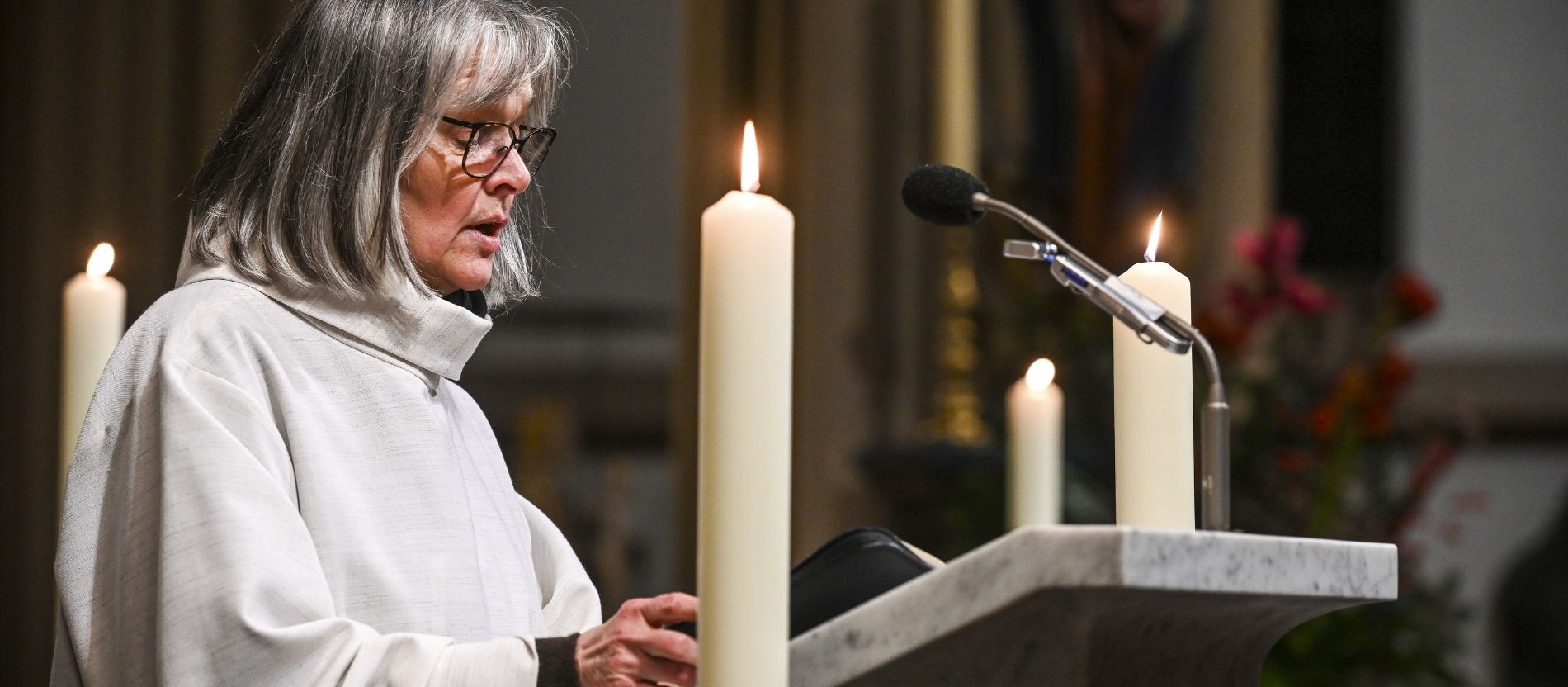 Eine Lektorin in liturgischer Kleidung liest die Lesung am Ambo