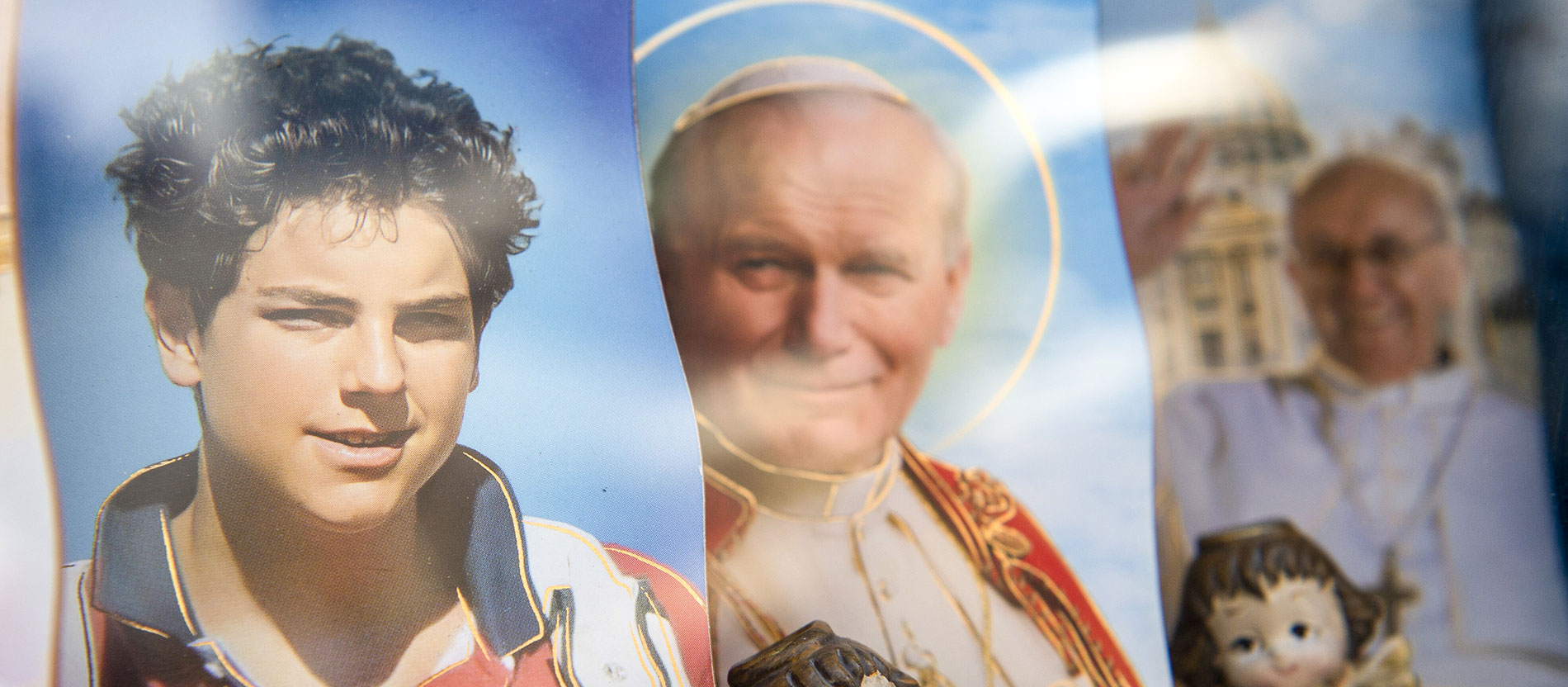 Bild von Carlo Acutis neben Bildern Papst Johannes Paul II. und Papst Franziskus in einem Souvernierladen