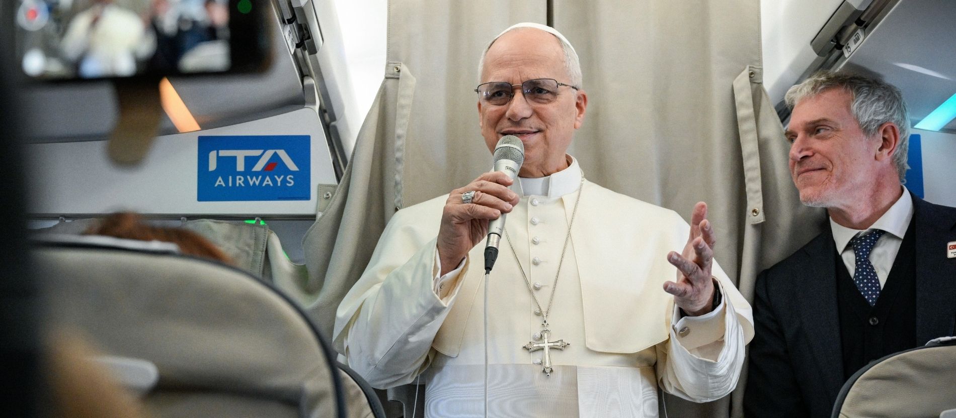 Papst Leo XIV. spricht im Flugzeug in eine Mikrofon