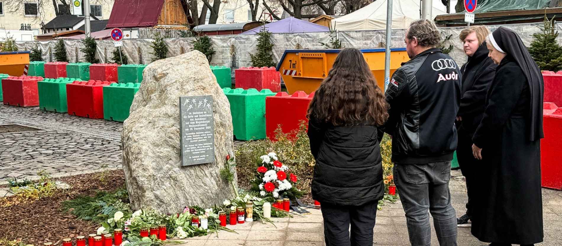 Am ersten Jahrestag stehen Menschen vor dem Gedenkstein, in Gedenken an die Opfer und Betroffenen des Weihnachtsmarkt-Anschlags, am 20. Dezember 2025 in Magdeburg.