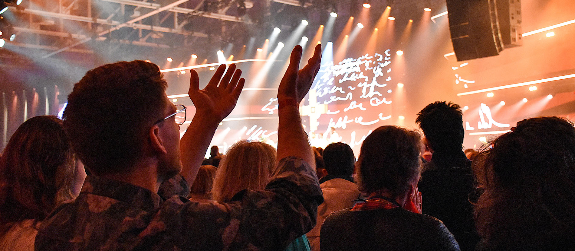 Teilnehmer beim Gottesdienst mit zum Gebet erhobenen Händen