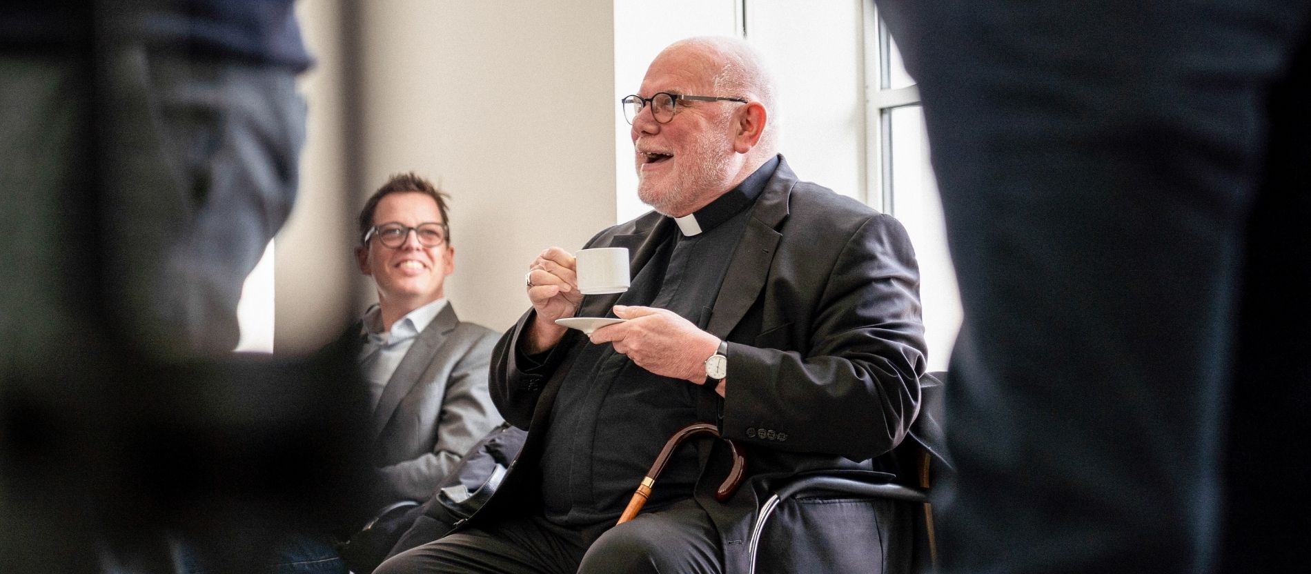 Kardinal Reinhard Marx lacht bei einer Kaffeepause