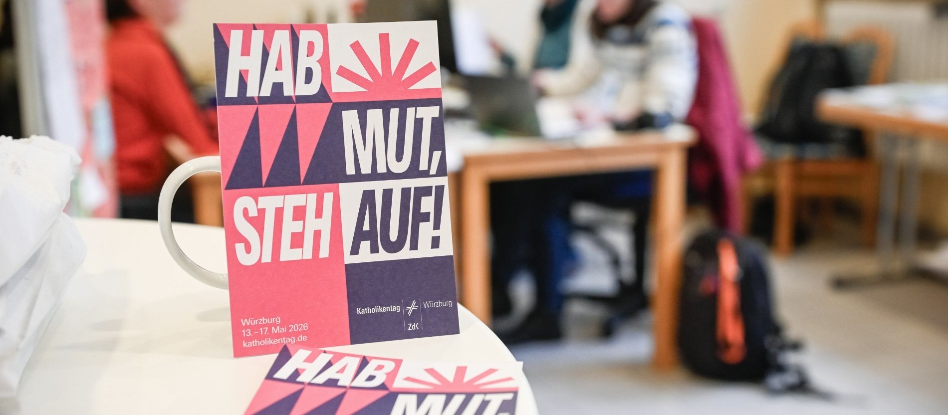 Karten mit dem Leitspruch des 104. Deutschen Katholikentags "Hab Mut, steh auf!" in einem Büro