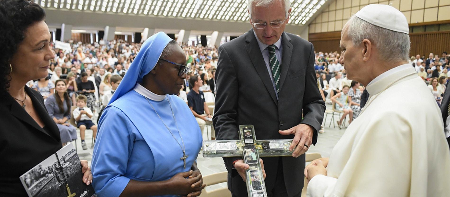 Der Papst schaut sich das Kreuz aus alten Handys an.