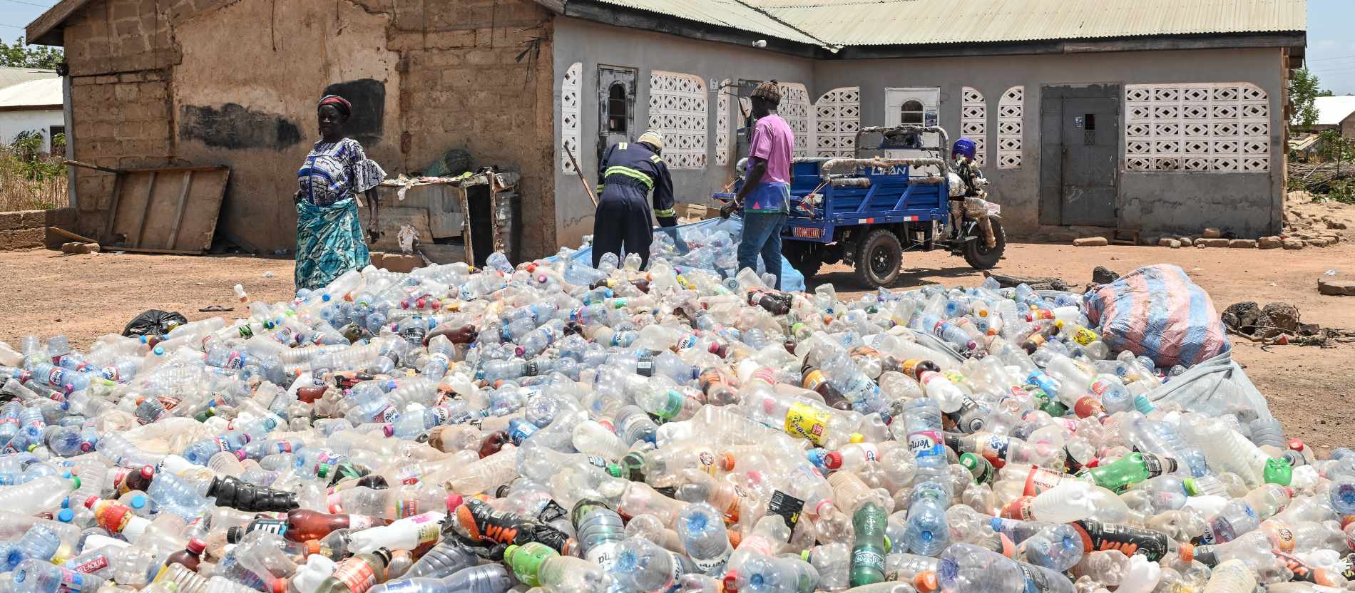 Yaro Seidu (m.) und sein Partner Al Hassan schieben leere Plastikflaschen zu einem 50 Kilo schweren Netz zusammen, am 26. März 2026 in Tamale (Ghana).