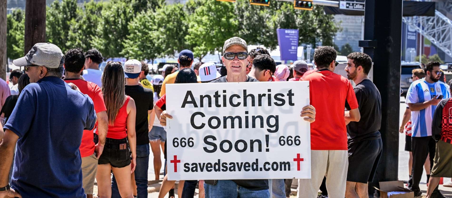 Ein Mann hält ein Plakat mit der Aufschrift "Antichrist coming soon" vor einem Fußballstadion in den USA