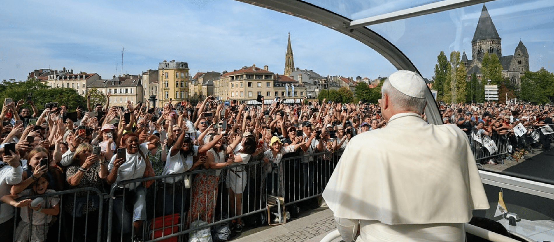 Papst Leo XIV. fährt im Papamobil an einer Menge aus Menschen vorbei. Sie strecken die Arme nach oben.