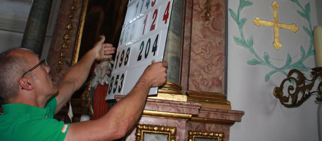 Damit die Gottesdienstbesucher erfahren, welche Lieder wann gesungen werden, stellt der Küster eine Anzeigetafel auf. 