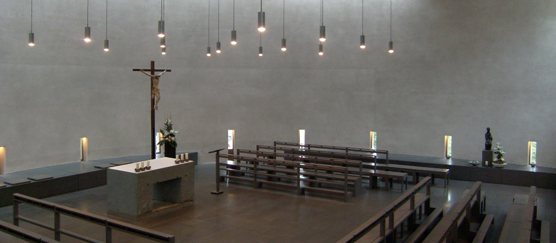 Blick auf den Altar in einer Kapelle umgeben von leeren Sitzreihen