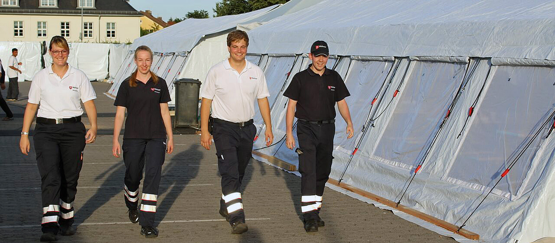 Vier Malteser vor Großraumzelten