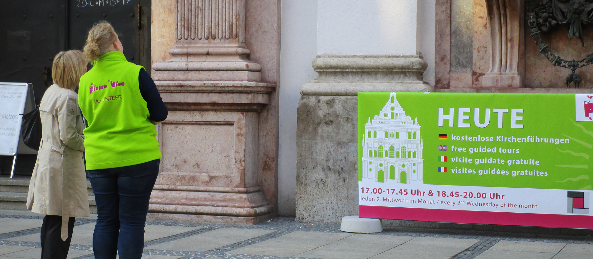 Eine Kirchenführerin erklärt einer Besucherin die Kirchenfassade.