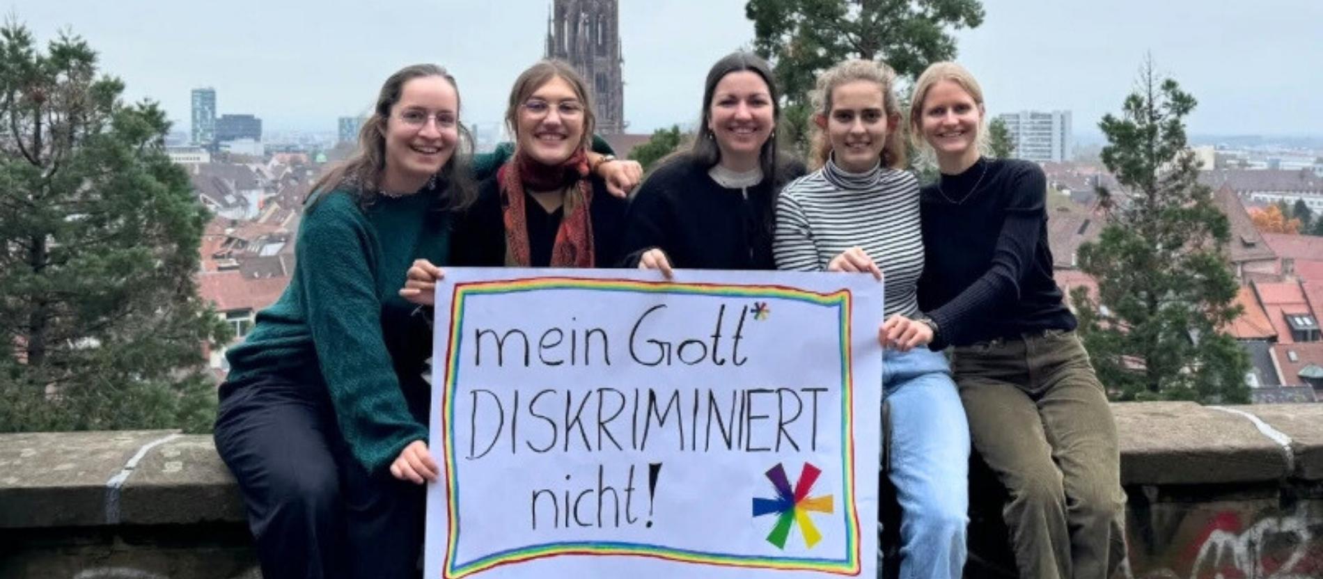Hier halten fünf Theologie-Studierende ein Plakat mit der Aufschrift 