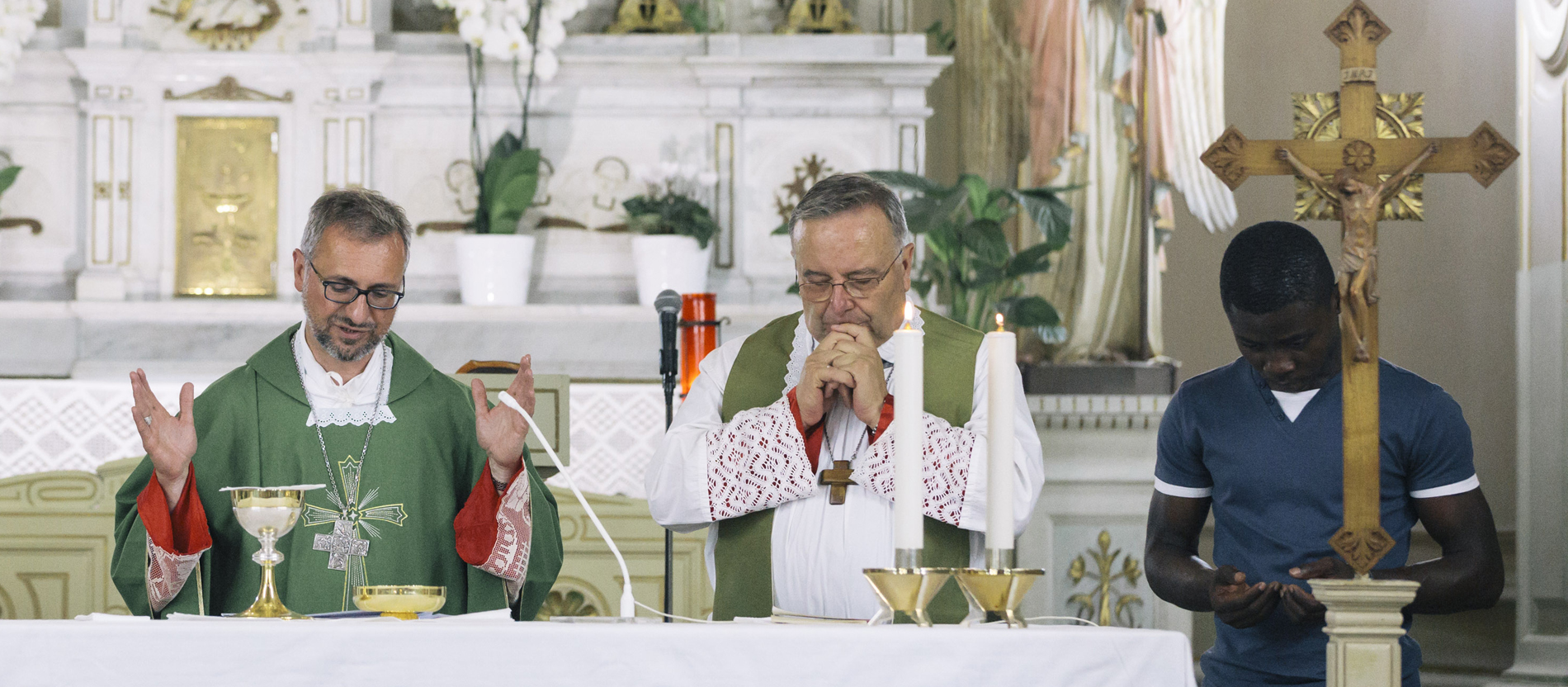 Ein Geistlicher und ein Flüchtling stehen zusammen in einer Kirche am Altar.