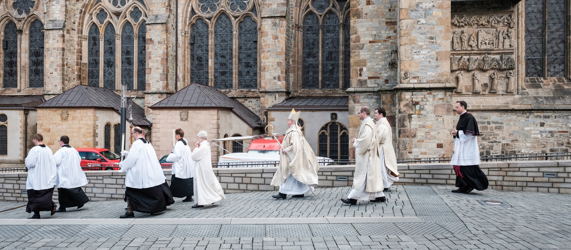 Vor einem Pontifikalamt gehen Zelebrant und Messdiener über den Domplatz in Paderborn.