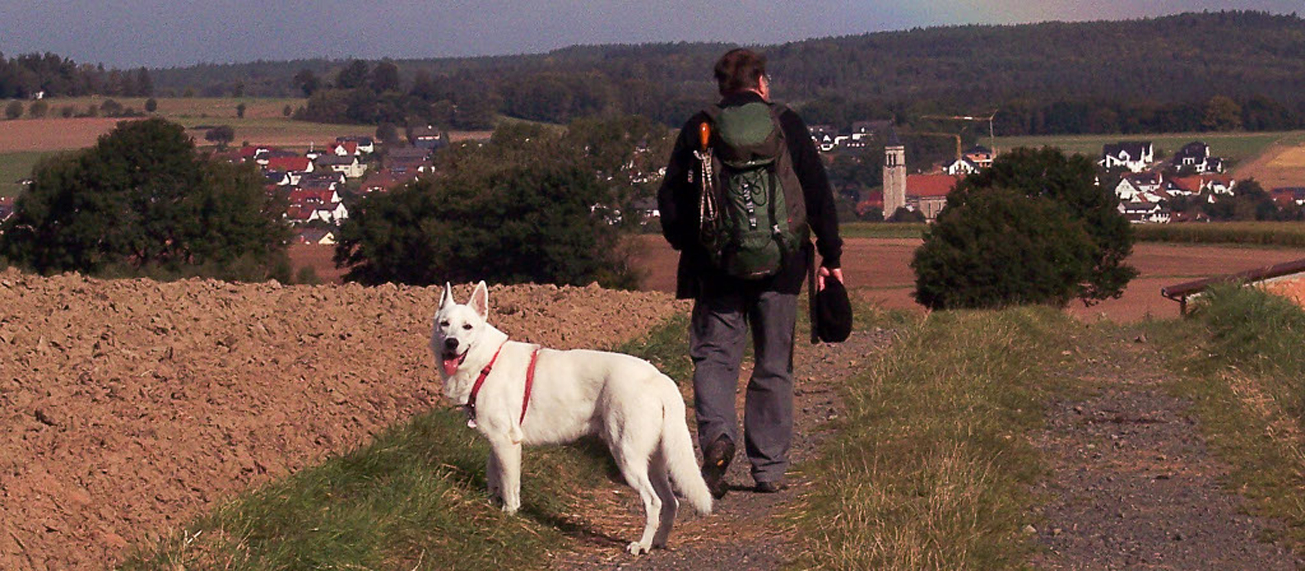 Pfarrer Hans Blamm in Wanderkluft mit seinem weißen Schäferhund 