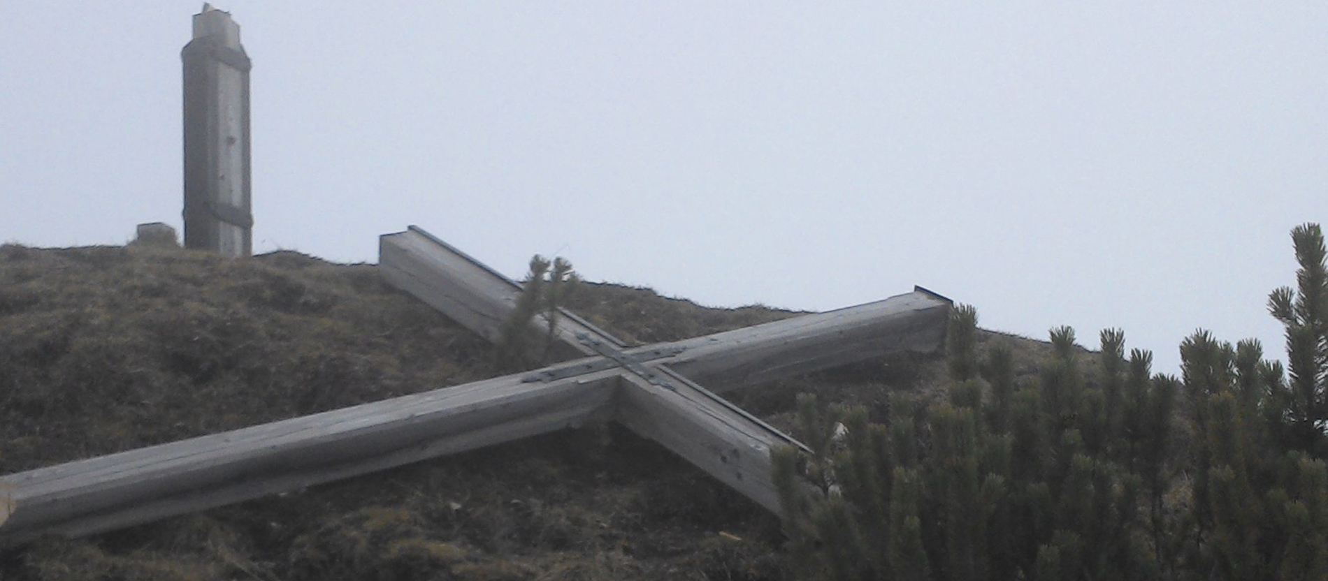 Ein großes Kreuz liegt auf dem Boden auf einem Berggipfel
