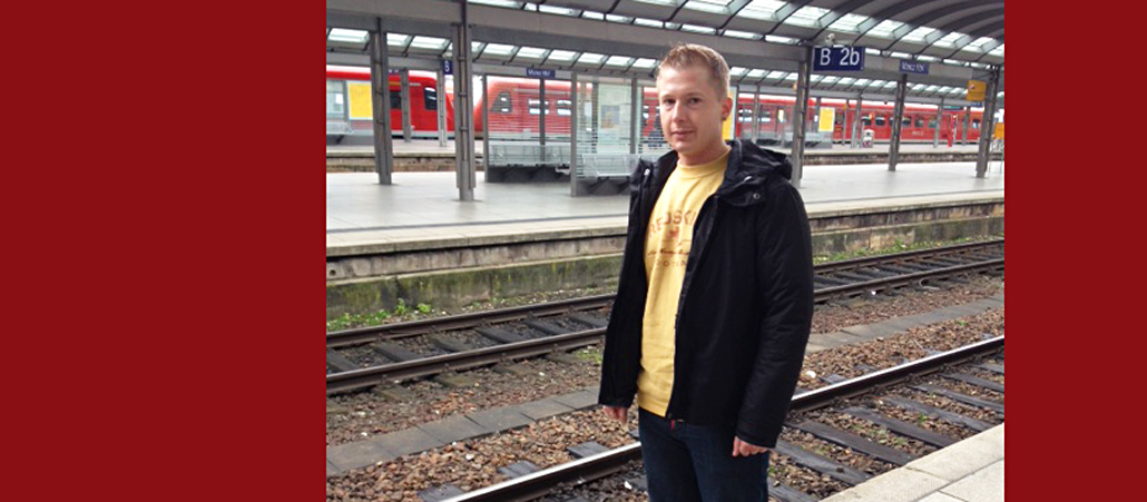 Blonder junger Mann am Bahngleis