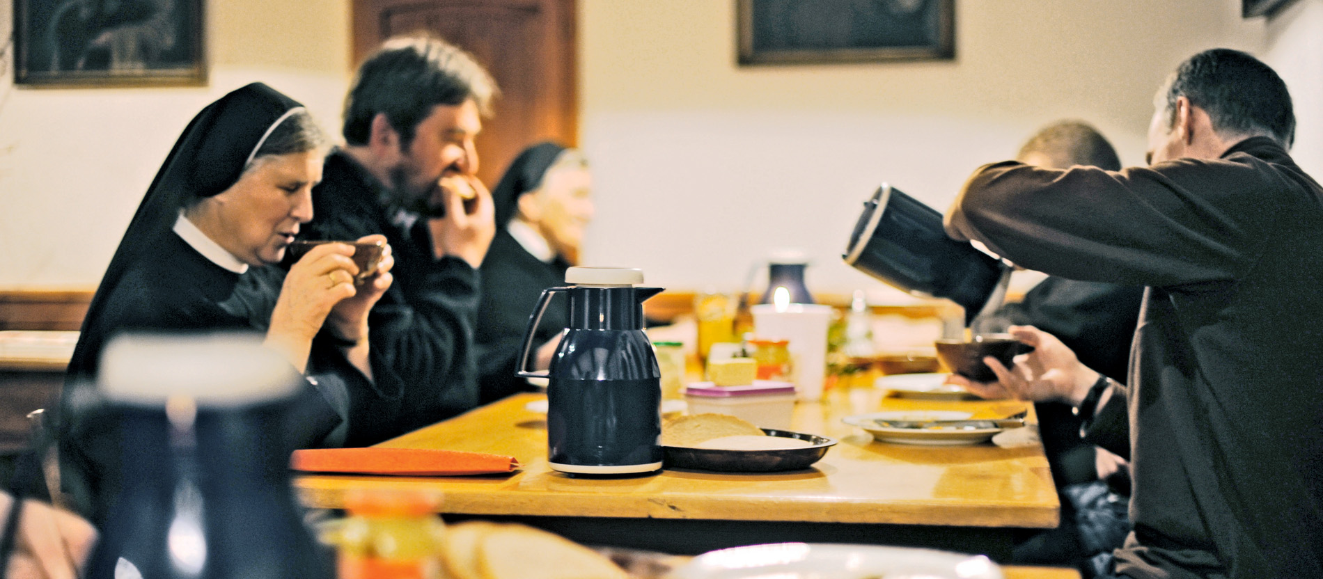 Ordensleute im Kloster Stühlingen sitzen zum Essen an langen Holztischen.