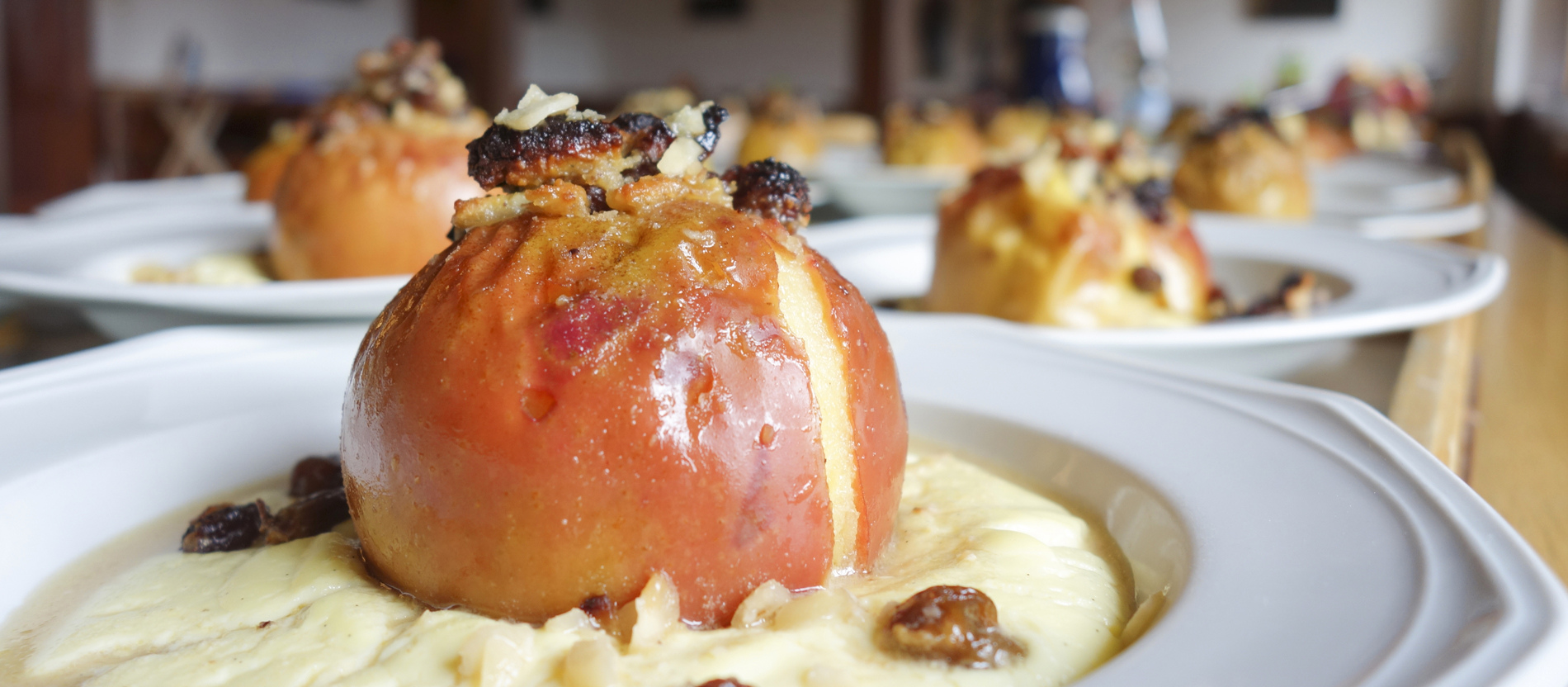 Auf einem Tisch stehen angerichtet heiße Bratäpfel in Vanillepudding.