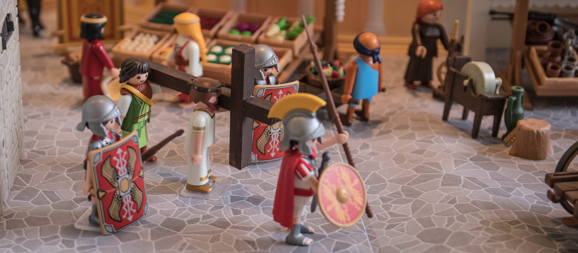 Playmobilfiguren stellen eine Kreuzwegstation nach: Simon von Cyrene hilft Jesus das Kreuz tragen.