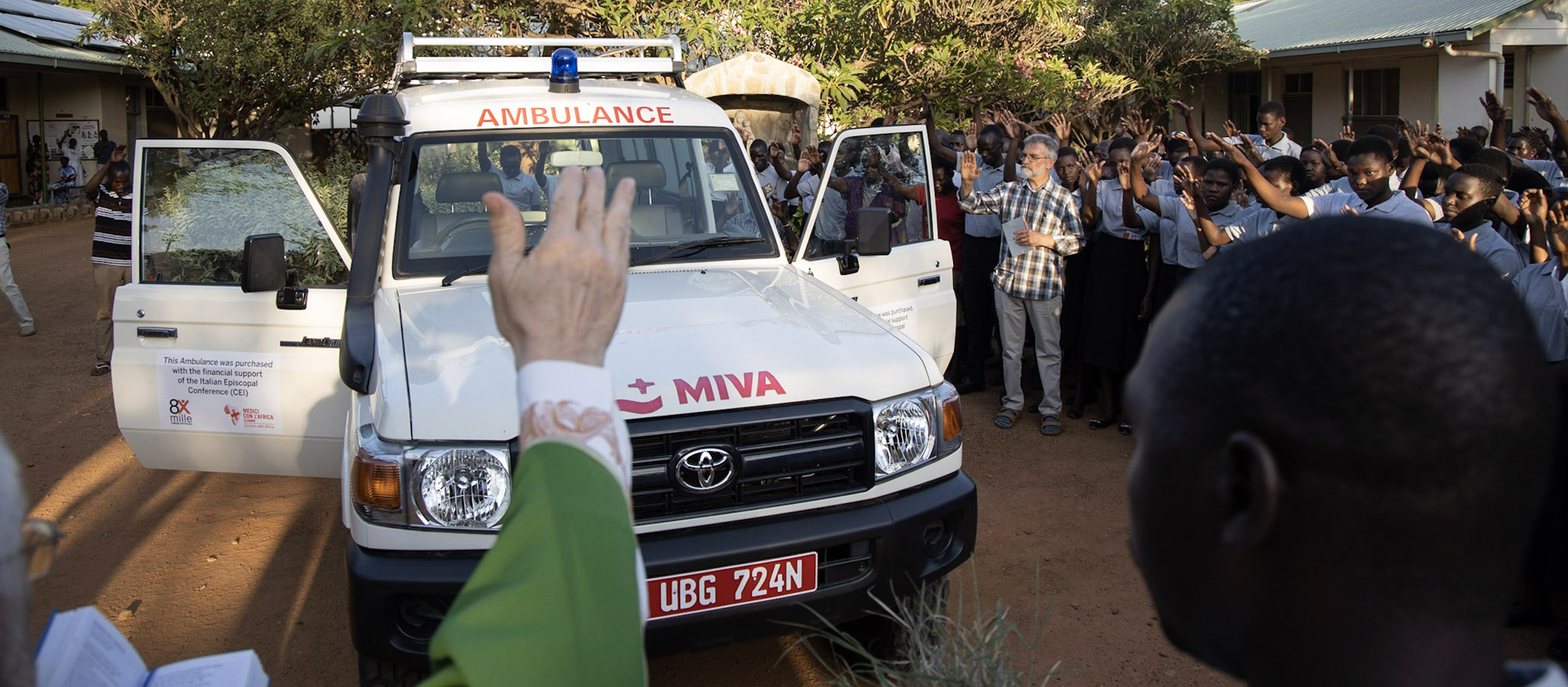 Ein Priester segnet einen neuen Krankenwagen des St. Kizito Hospitals in Matany. Bruder Günther Nährich steht im Hintergrund.