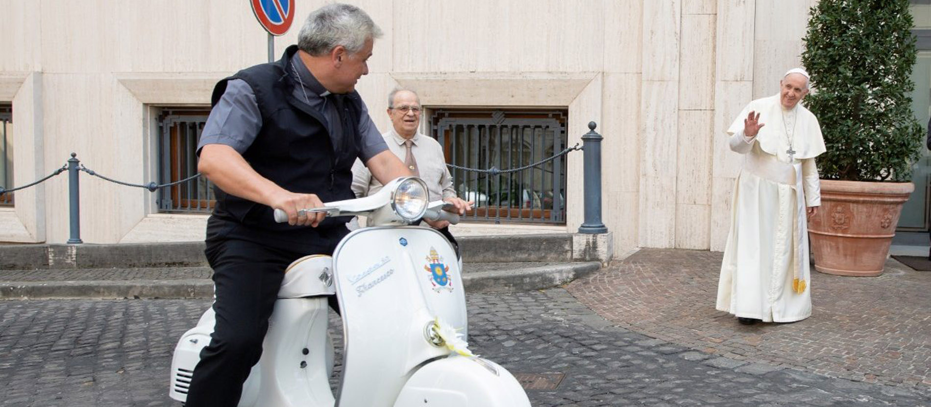 Kardinal Konrad Krajewski probiert eine weiße Vespa aus