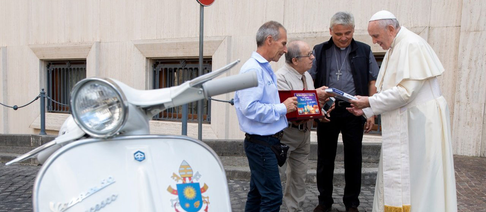 Papst Franziskus bekommt eine weiße Oldtimer-Vespa geschenkt. 